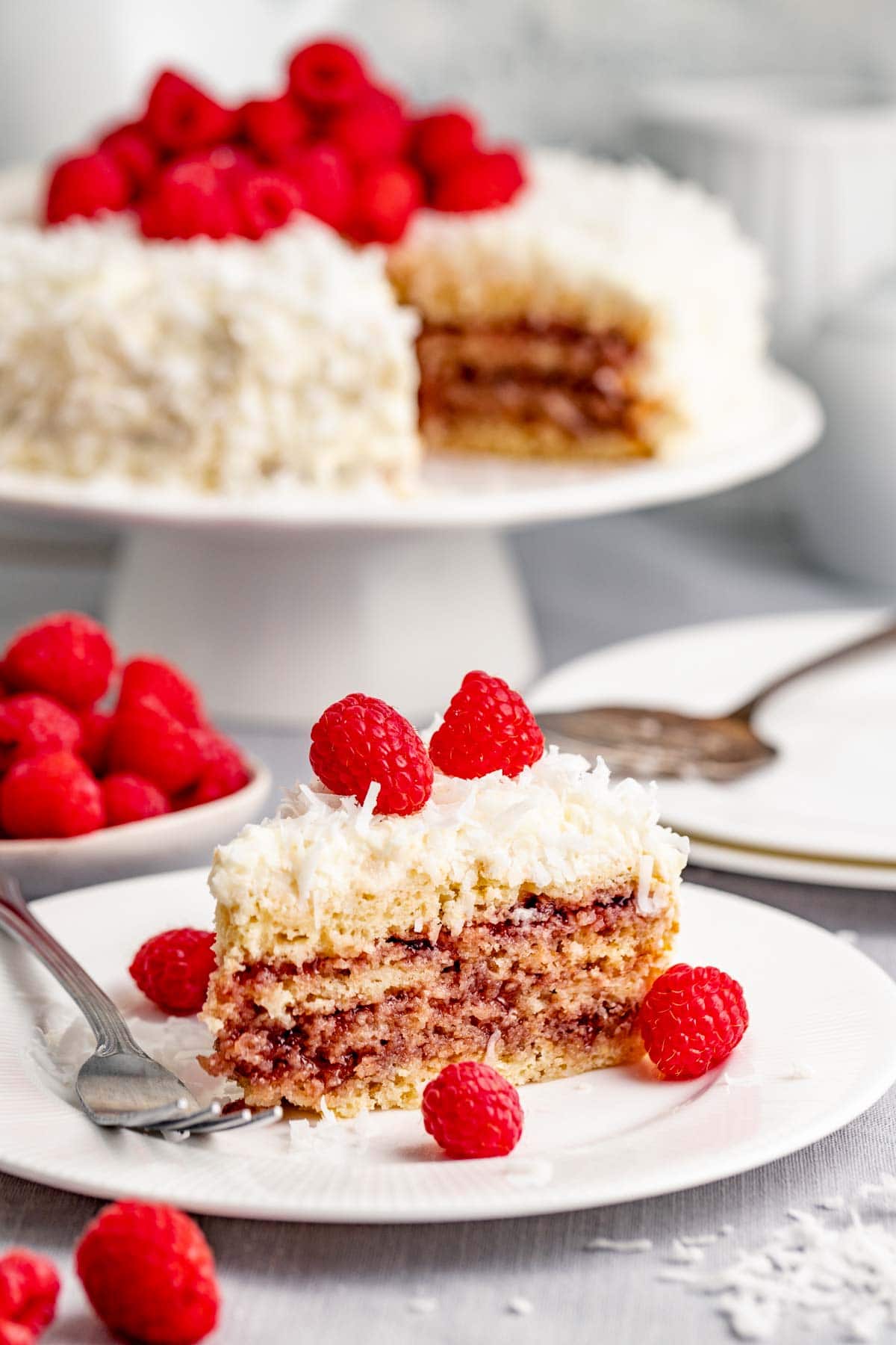 a slice of the cake on a plate with the cake in the background on a cake stand