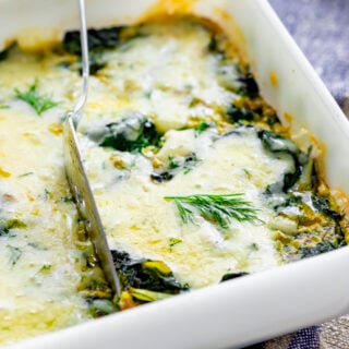 the chard bake in a white casserole dish with a serving utensil slicing into it to cut a serving