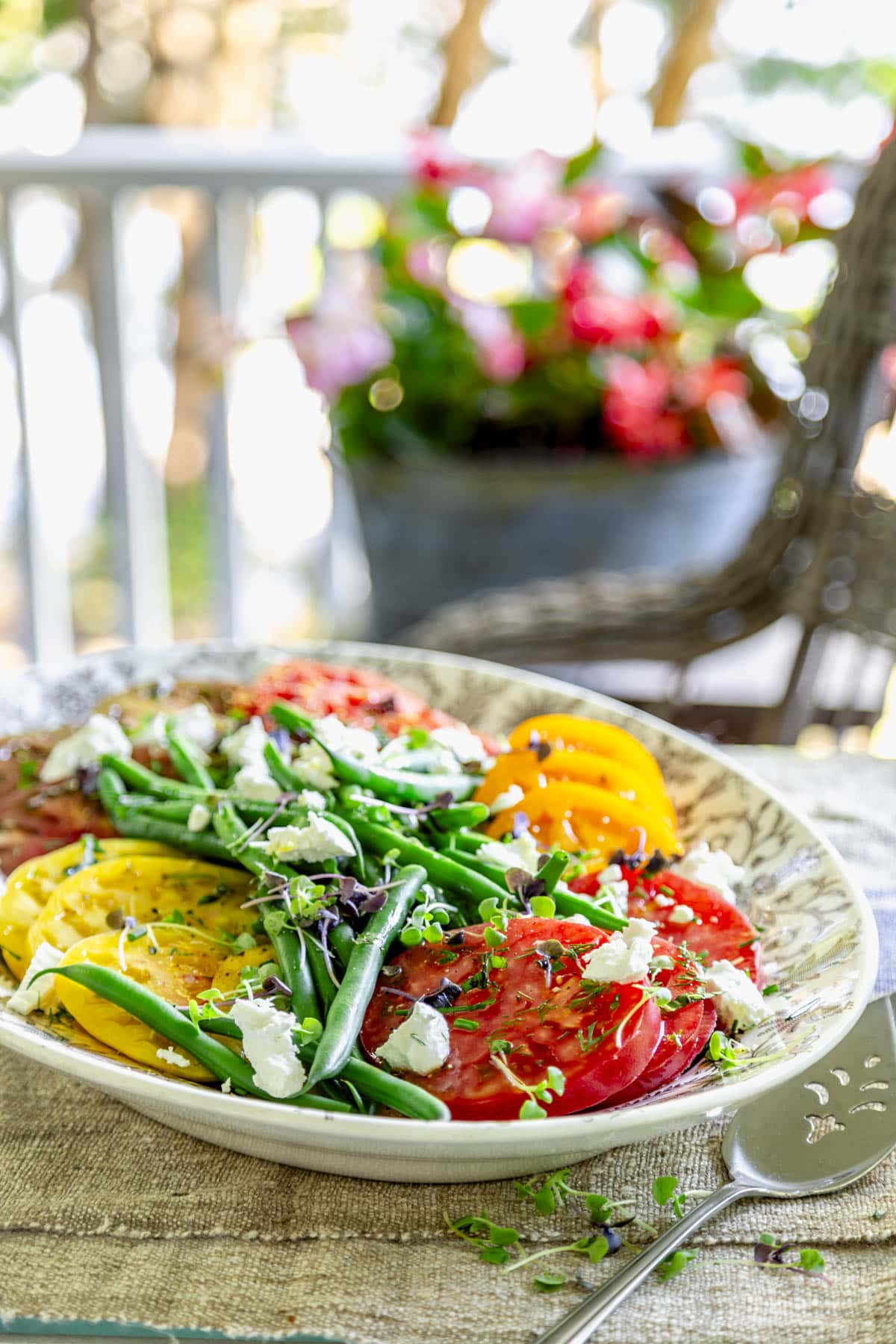 tomato green bean salad with a rocking chair and begonias in the background