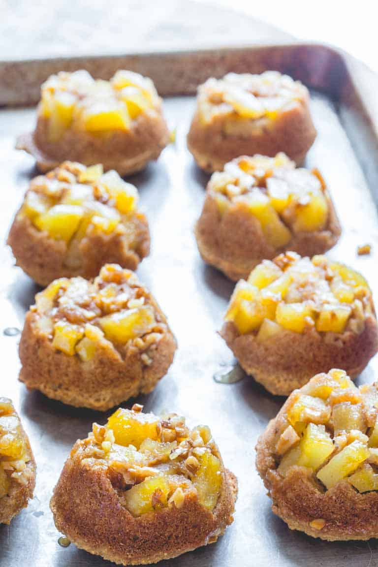 Upside-down apple muffins placed on a rimmed baking sheet.