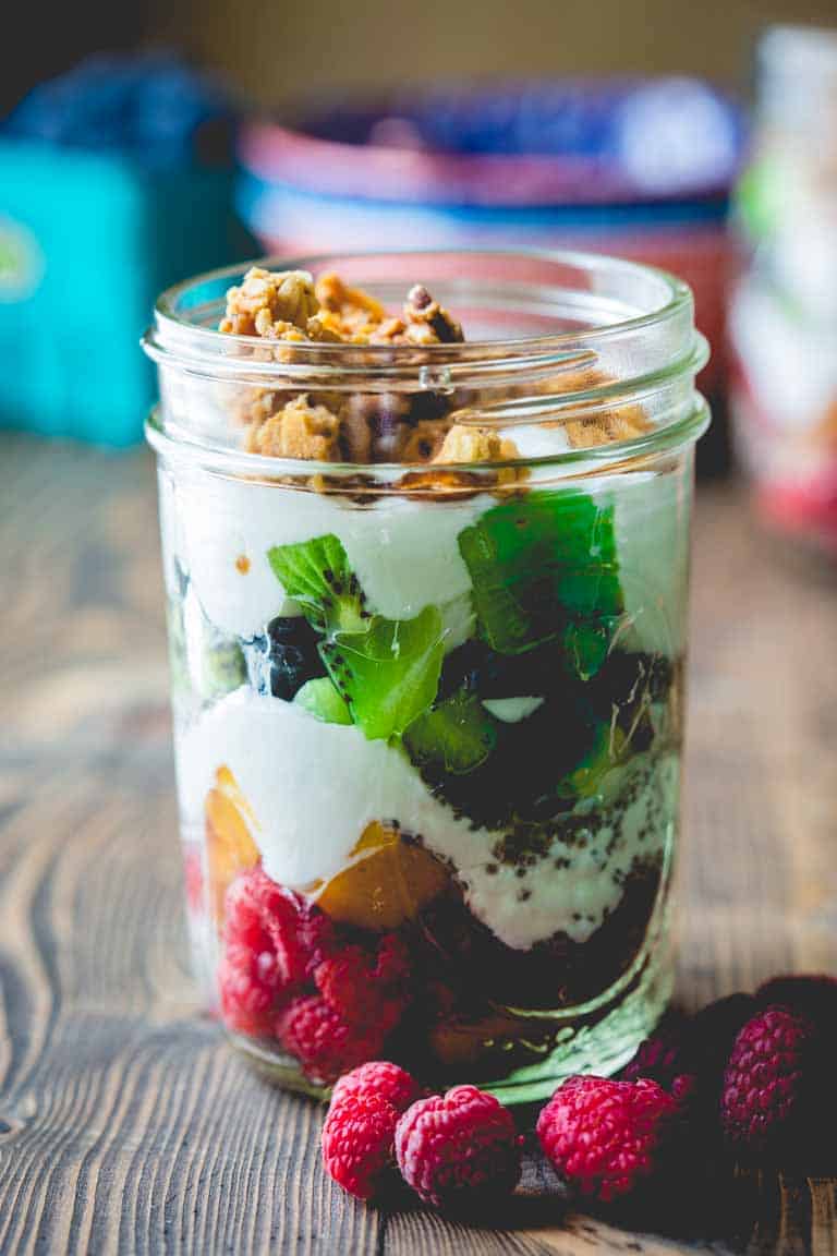 A close up image of Healthy Rainbow Fruit and Yogurt Parfaits in a jar
