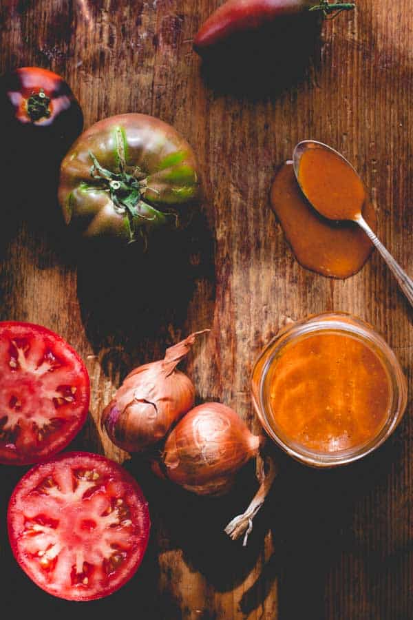 Smoky Tomato Shallot Dressing on a cutting board next to shallots and tomatoes