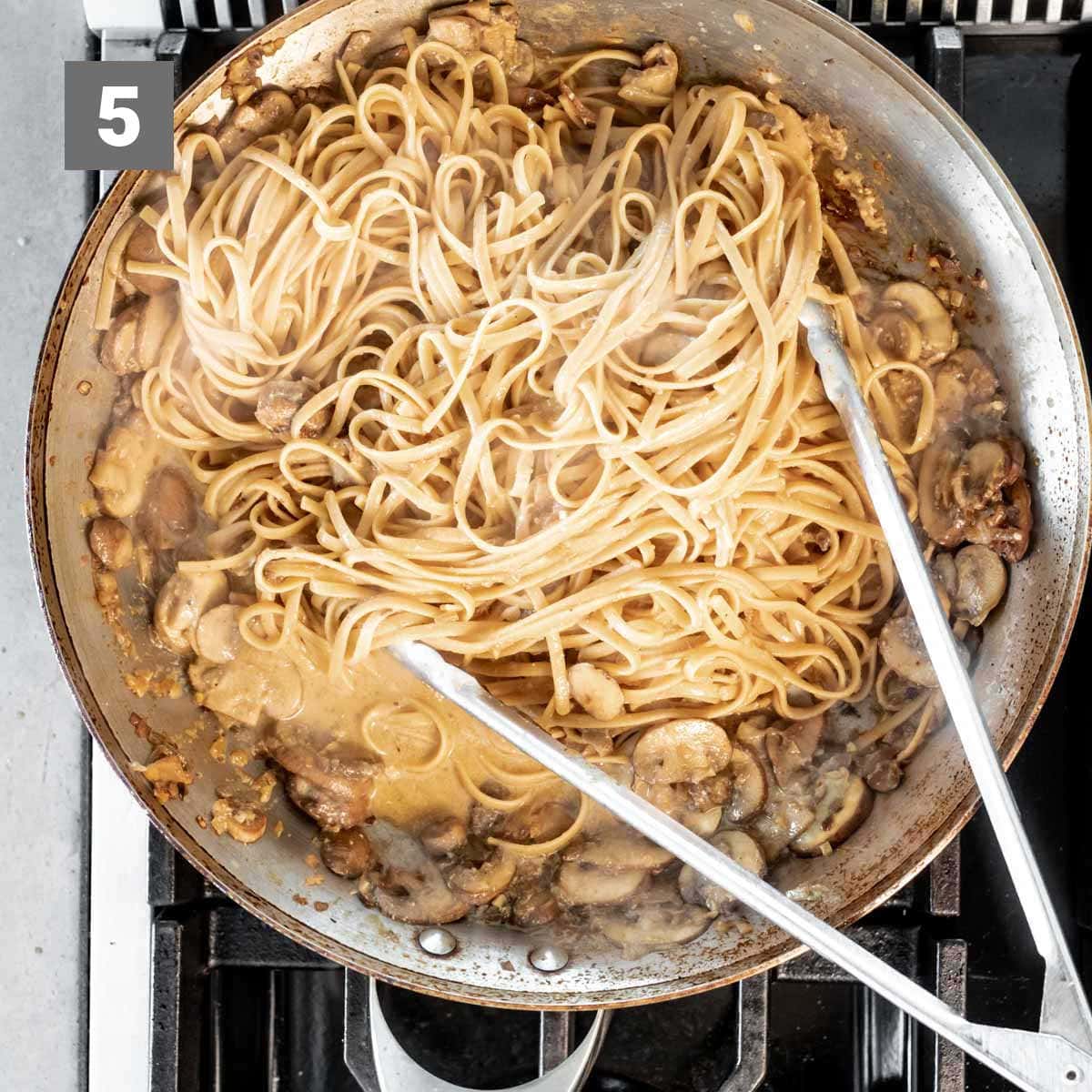 mixing the pasta with the mushrooms, eggs and cooking liquid