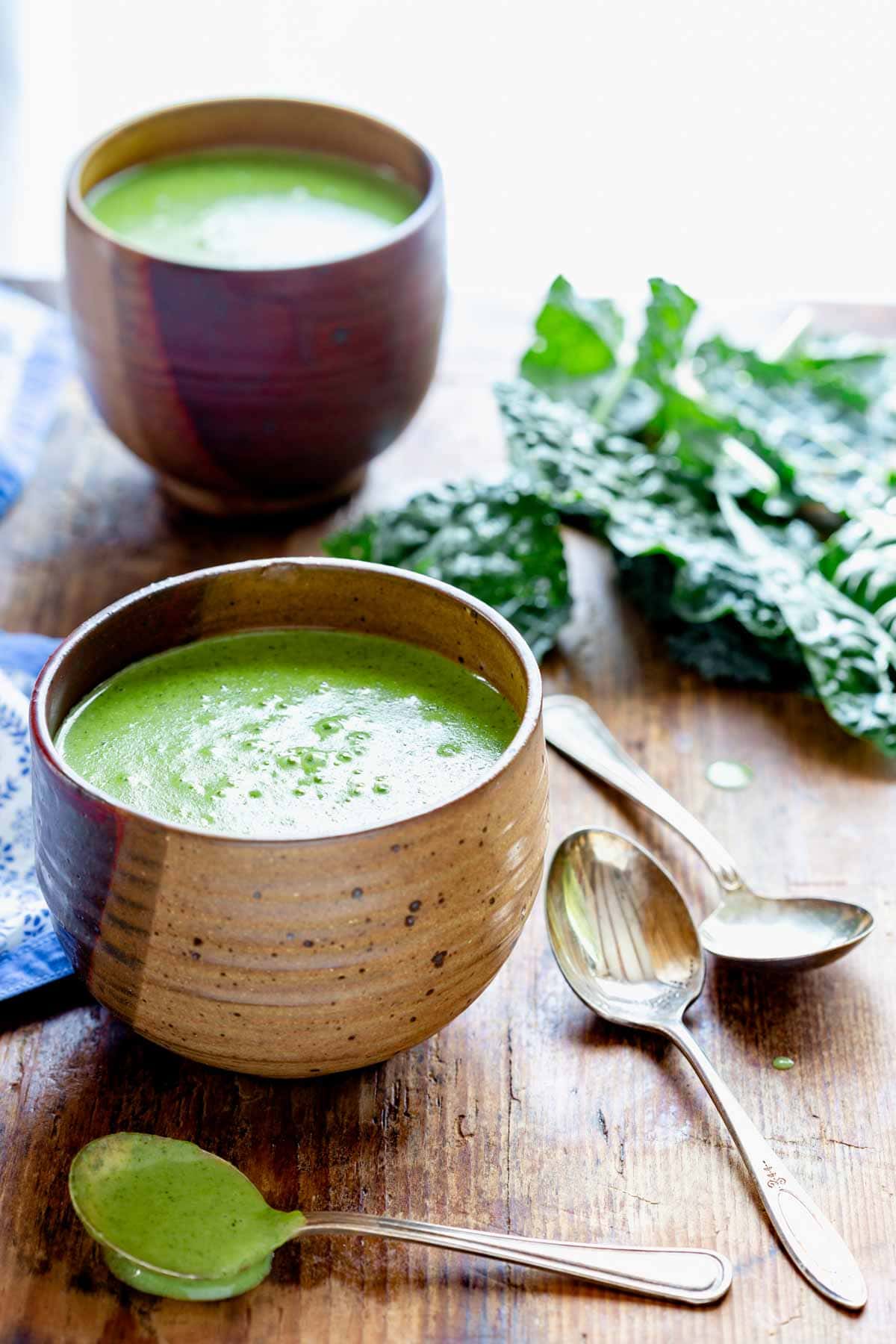 side view of the soup bowls with lacinato kale on a wooden board with soup spoons