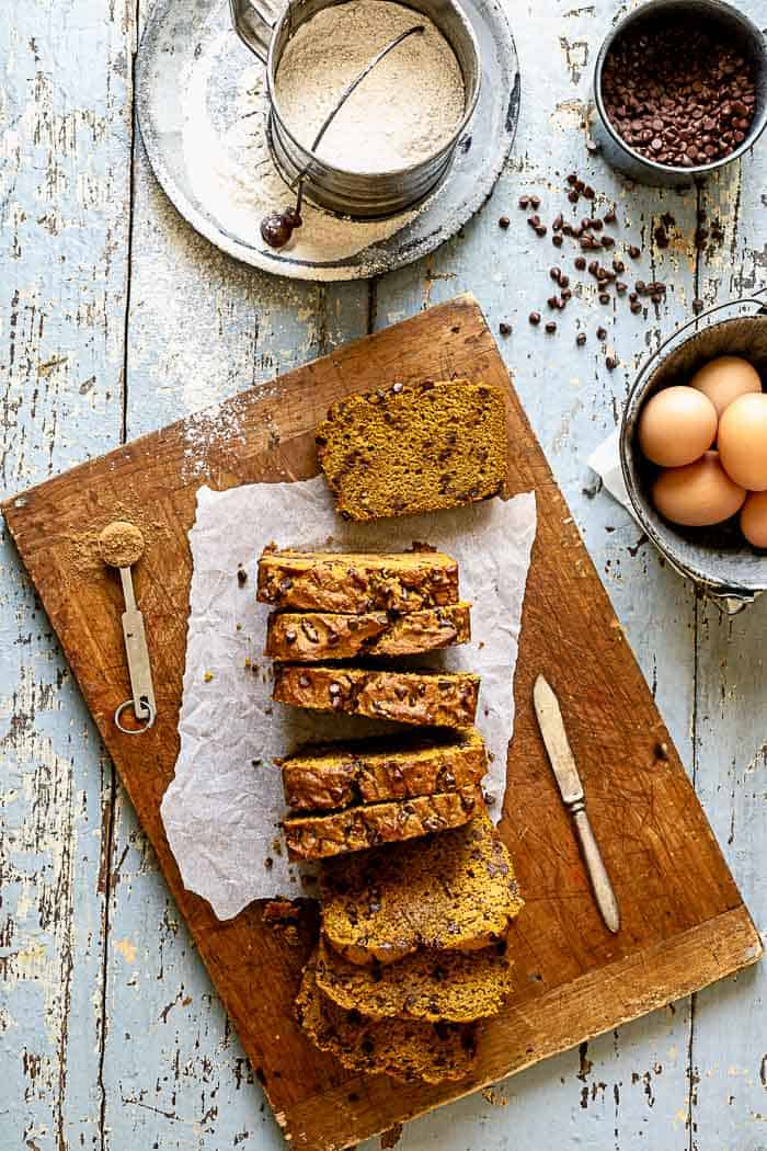 an overhead view of a sliced loaf of pumpkin bread on a blue table