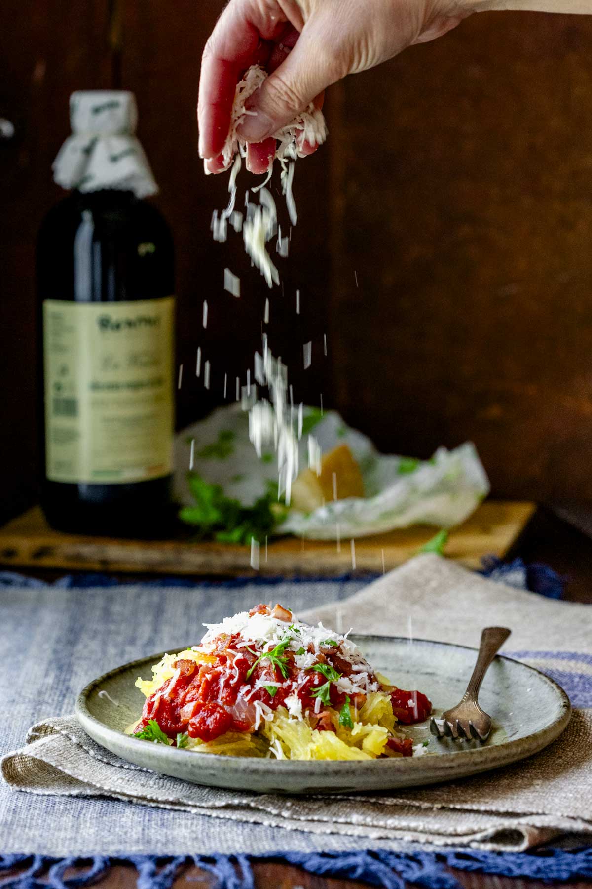 sprinkling Parmesan over the squash and sauce