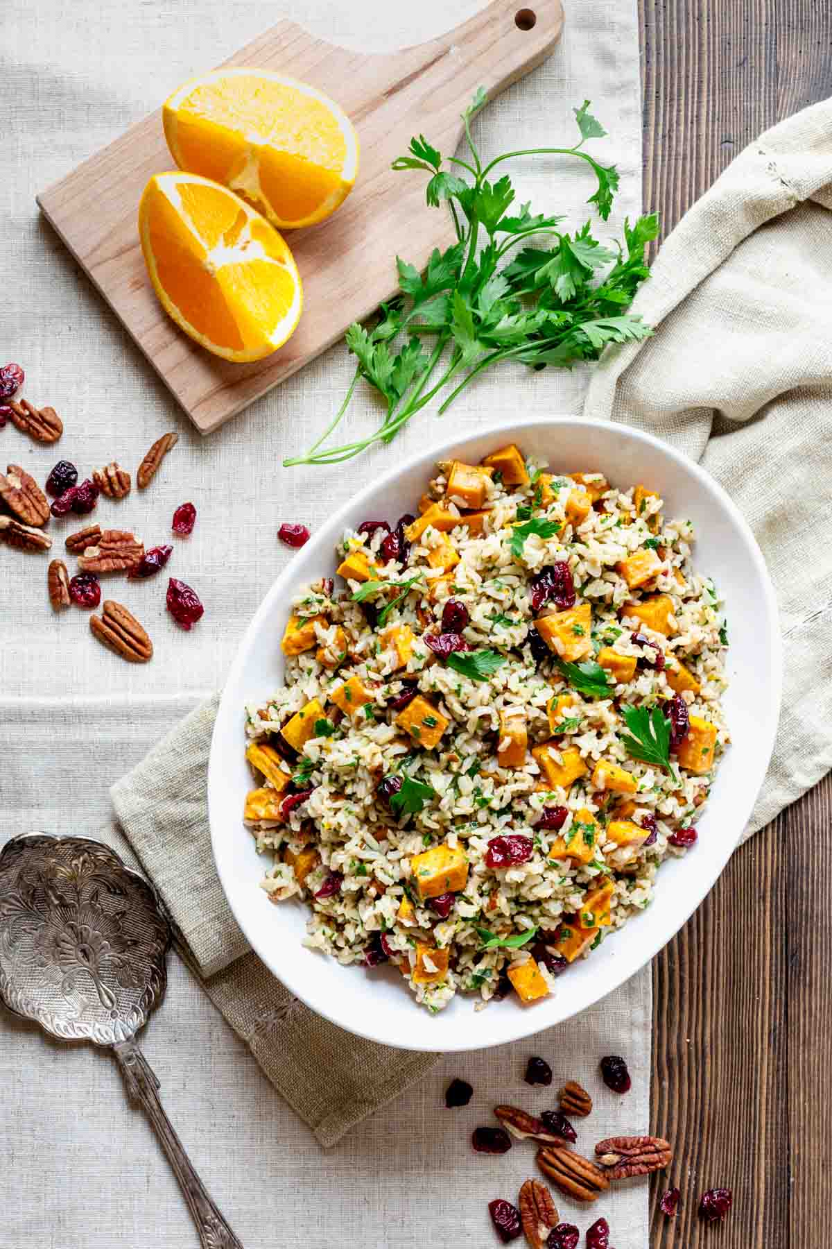 the salad with a cutting board with orange, pecans, cranberries and parsley