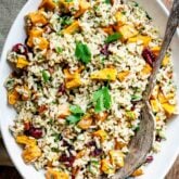closeup of oval white bowl filled with brown rice salad with chunks of roasted sweet potatoes in it