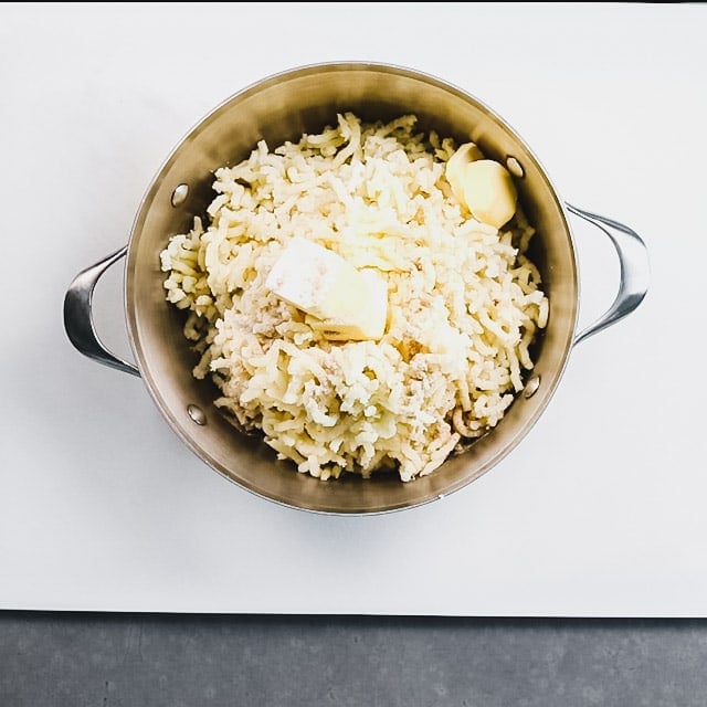 A pot with riced potato and butter in it