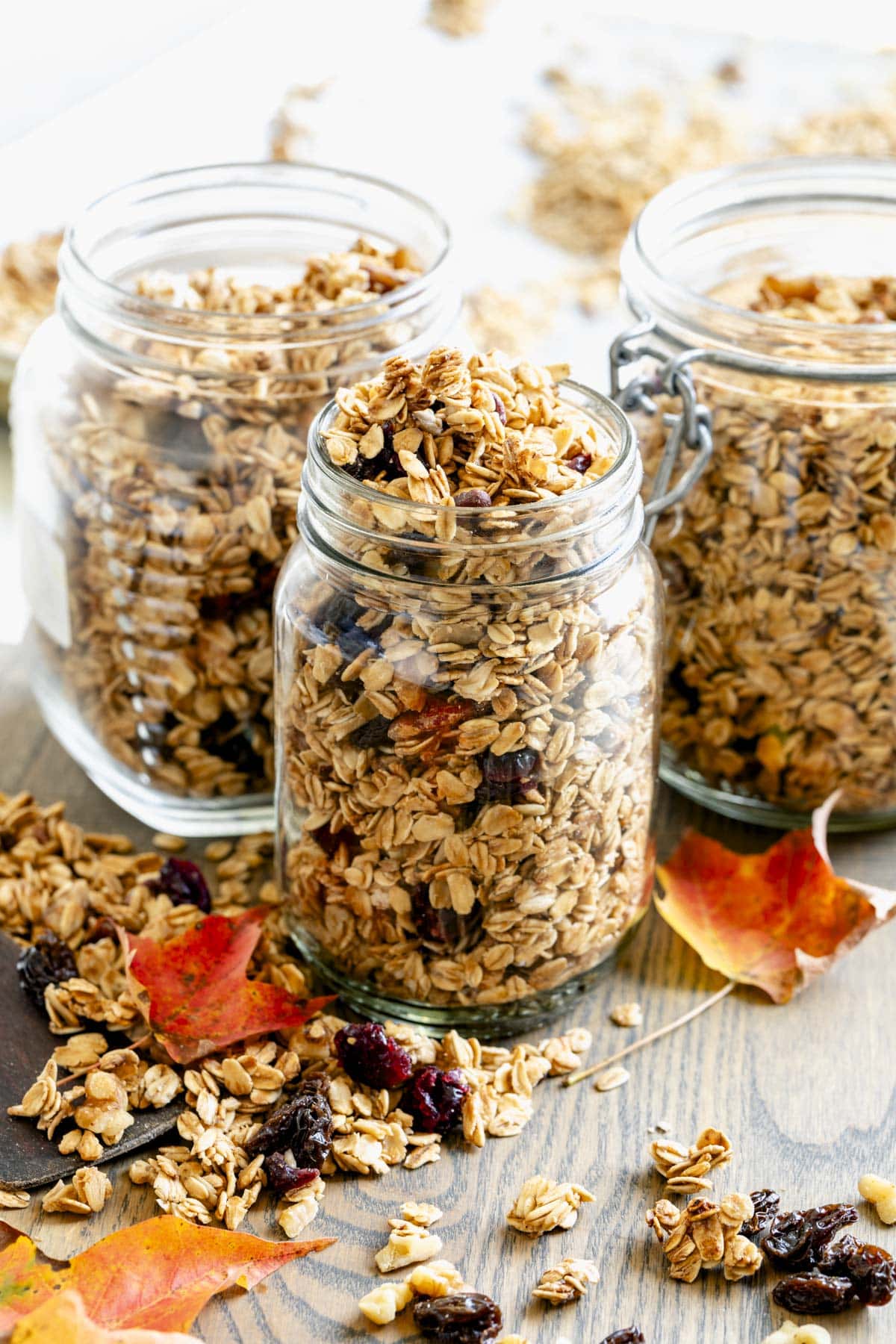 the jars of maple syrup granola on a cutting board with maple leaves