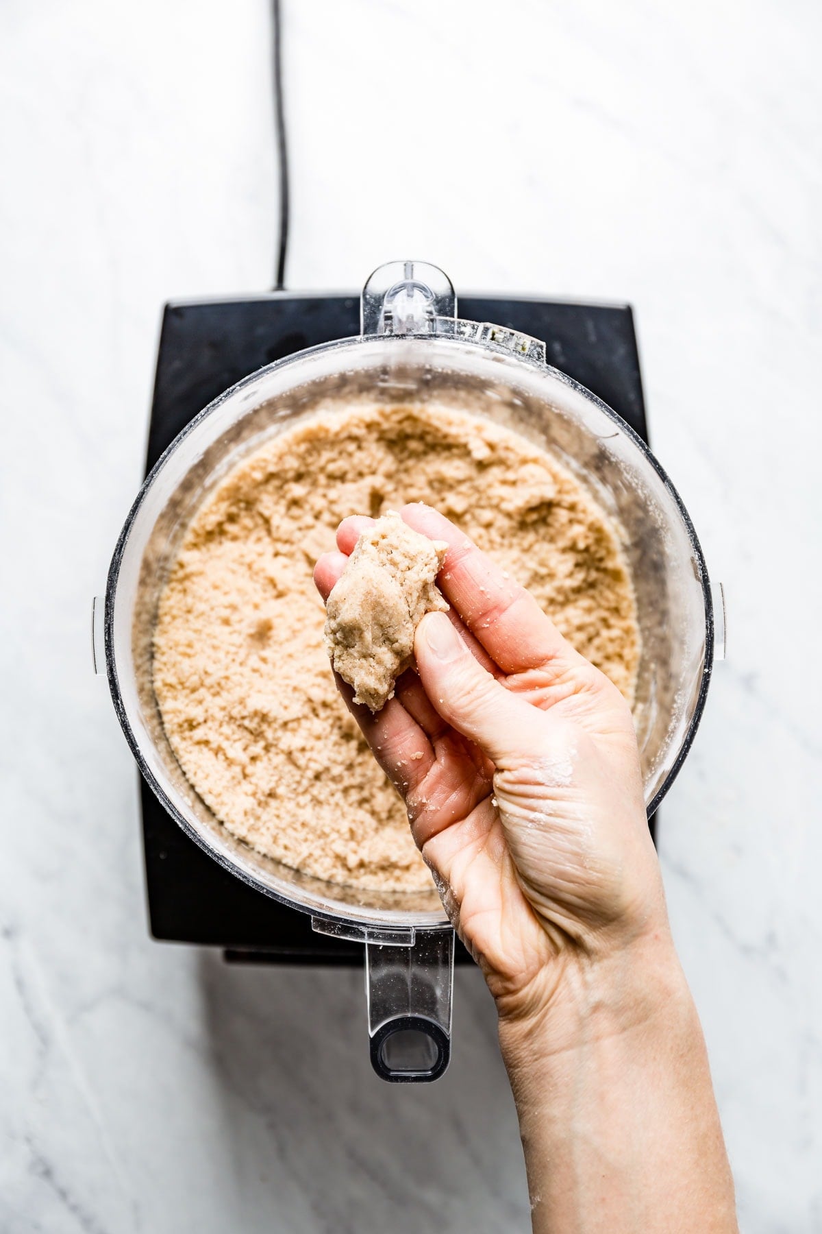 A person holding a piece of tart dough to show texture