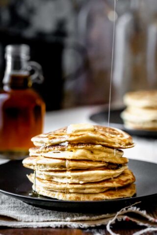 a stack of pancakes with maple syrup running over it