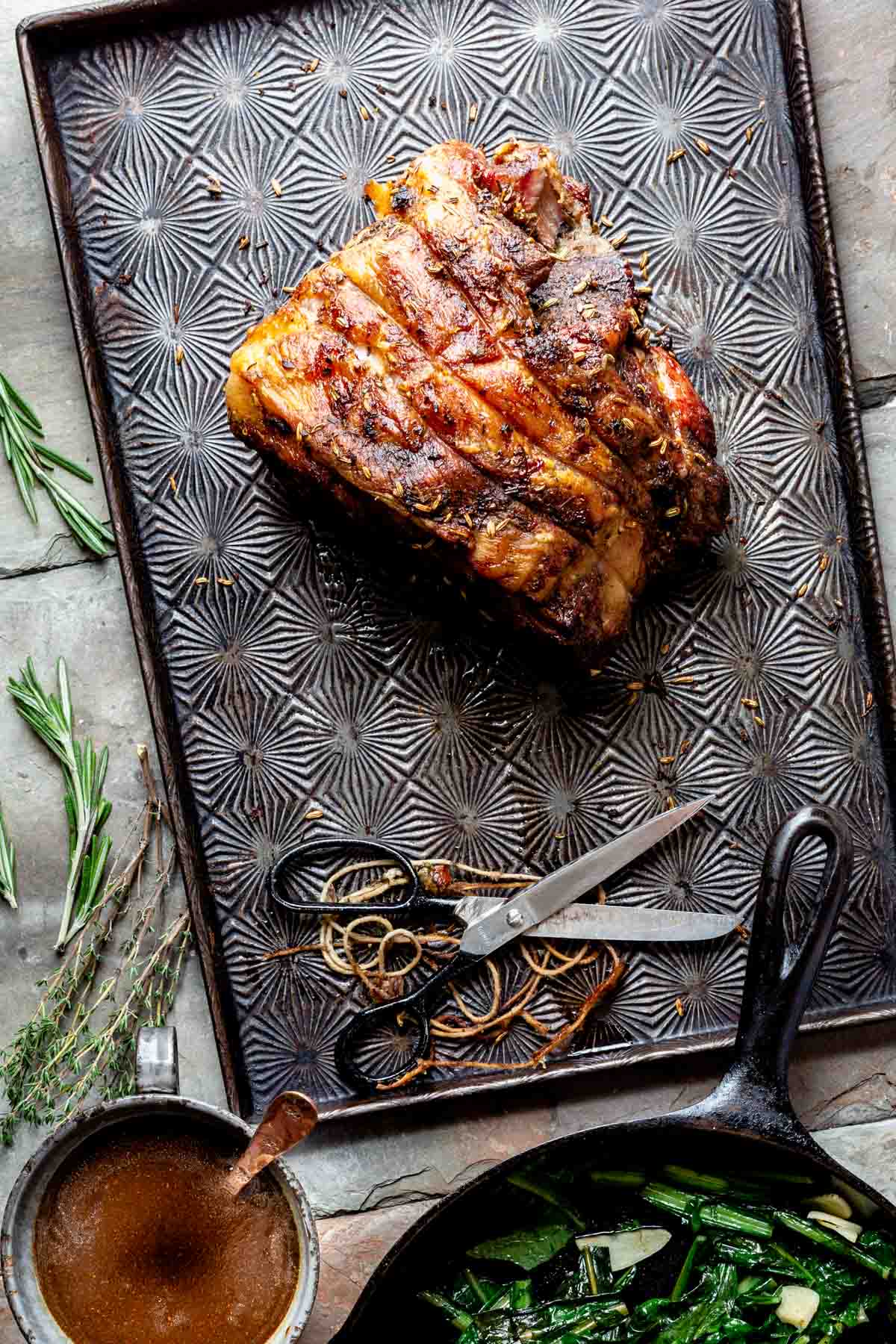 the whole roasted pork on a sheet pan before it has been cut with scissors and butcher's twine