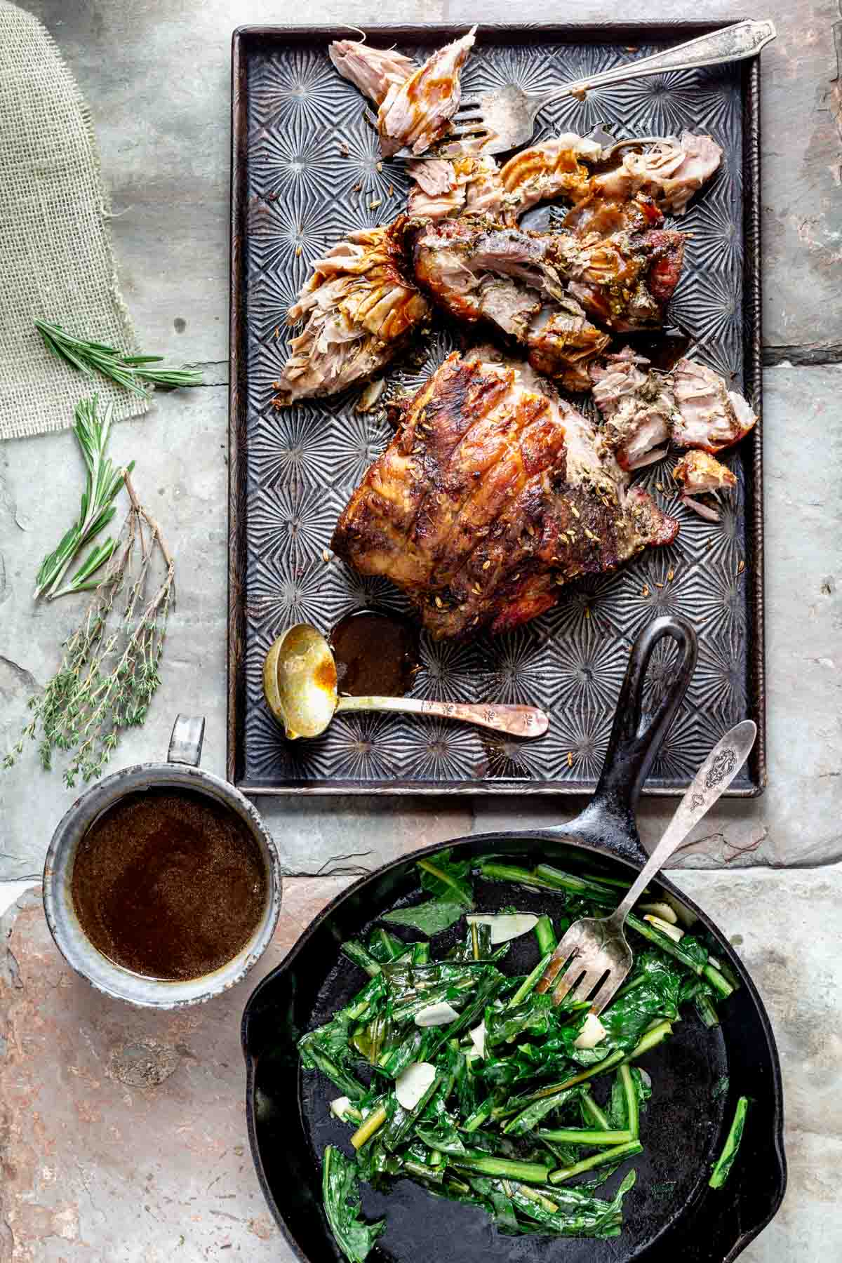 pork on a baking sheet and a skillet of sauteed mustard greens