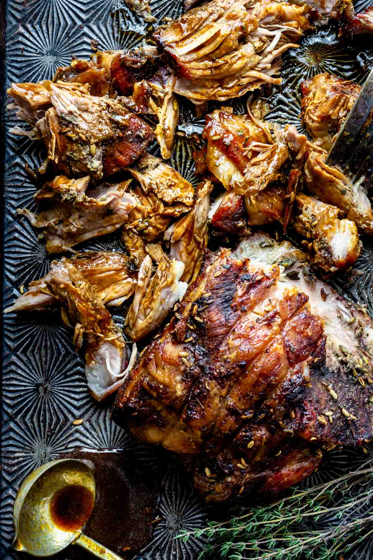 Slow roasted pork shoulder on a metal baking sheet with a hex pattern
