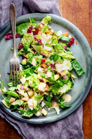 a teal plate with chopped salad on it with a fork