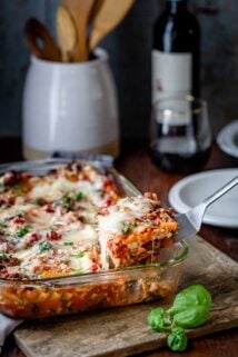 lifting a slice of lasagna out of the baking dish