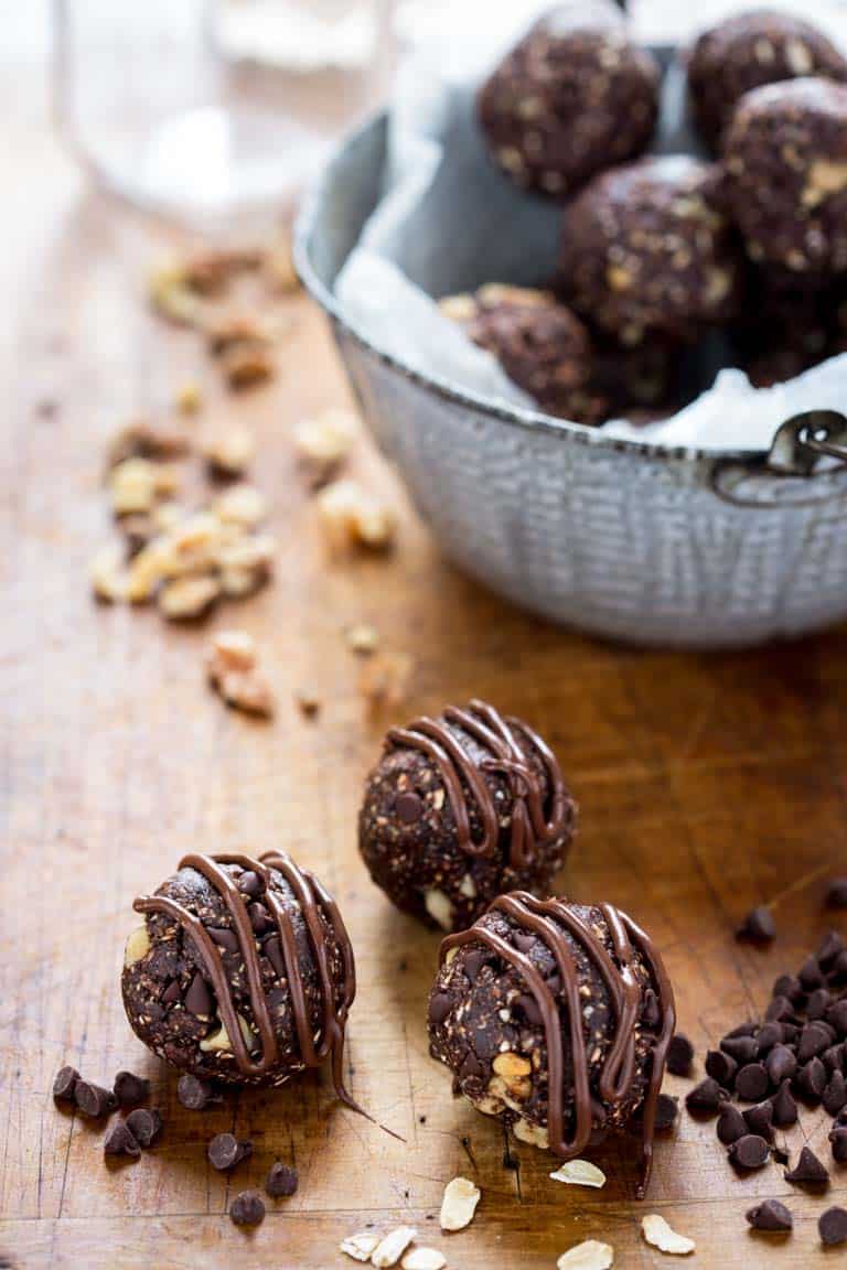 Dark chocolate walnut vegan energy balls on counter next to bowl.