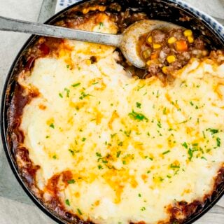 a close up of the shepherd's pie in a black skillet with a scoop removed