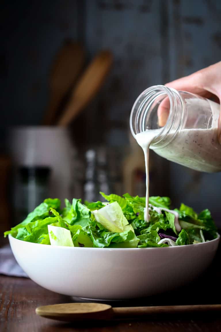 Horseradish ranch dressing being poured onto a salad 