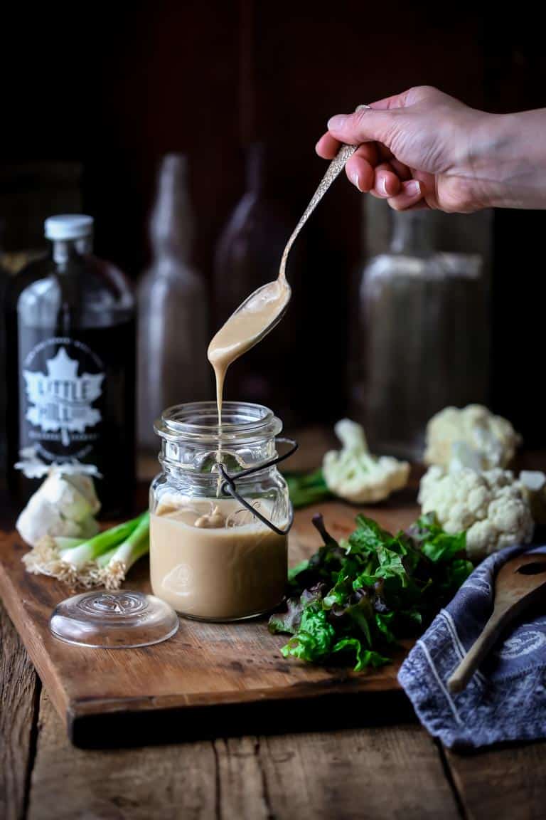Maple Tahini Dressing being drizzled into a jar