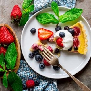 Celebrate the best of what Summer has to offer with this Red White and Blue Buttermilk Berry Tart! A lightly sweetened buttermilk custard is poured over a mix of fresh, plump and delicious summer berries and baked in an easy press-in crust and then topped with a dollop of whipped cream. The perfect warm weather dessert! | Healthy Seasonal Recipes | Katie Webster
