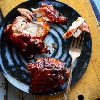 a blue plate with two chicken thighs on it