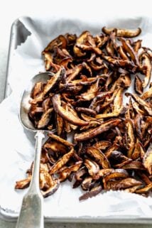 Cooked Shiitake Mushrooms on parchment paper on a baking tray with a spoon in them.