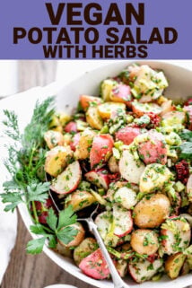 closeup overhead of potato salad in a white bowl with herb sprigs