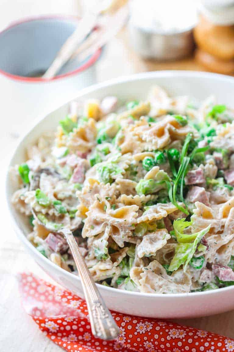 side view of the pasta salad with creamy dressing in a white serving bowl
