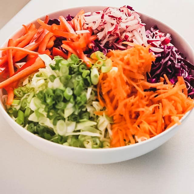 Add the cabbage, carrots, peppers, radishes and scallions.