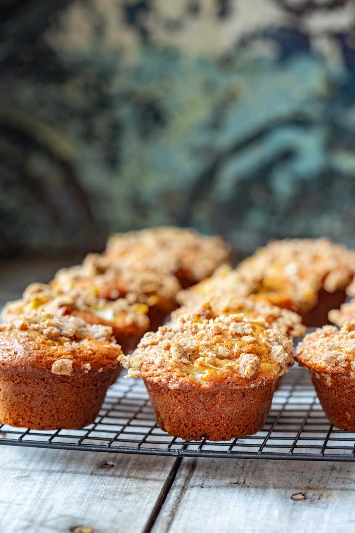 moody blue patina background with a batch of apple muffins cooling on a baking rack