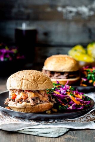 two plates with pulled beef sandwiches and coleslaw