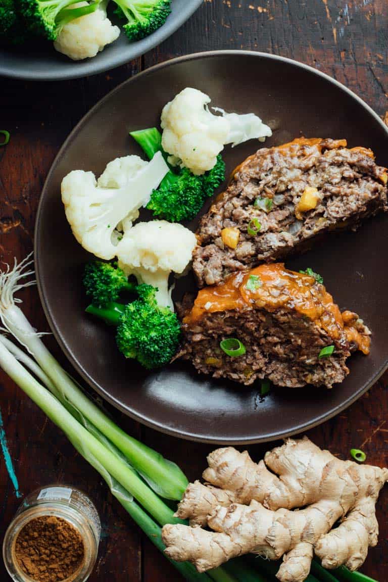 Asian meatloaf on a brown plate alongside broccoli and cauliflower
