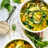 chicken quinoa soup in two bowls with a measuring cup of quinoa on the table next to them