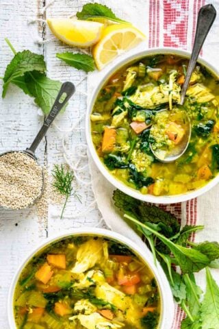 chicken quinoa soup in two bowls with a measuring cup of quinoa on the table next to them