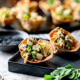 two of the wonton cups on a black plate from the side (closeup)