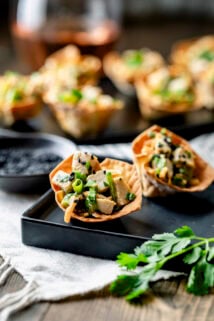 two of the wonton cups on a black plate from the side (closeup)
