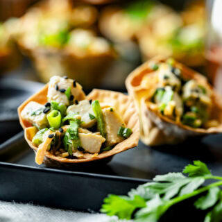 two of the wonton cups on a black plate from the side (closeup)