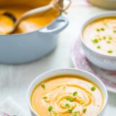 two bowls of soup and a pot of soup on a white table