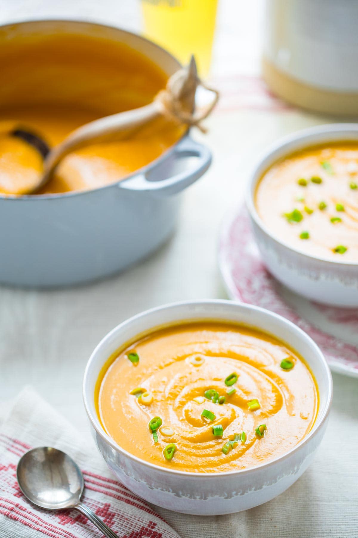 two bowls of soup and a pot of soup on a white table