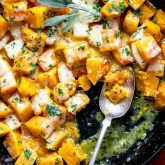 Easy cheesy butternut squash in a cast iron pan with a spoon