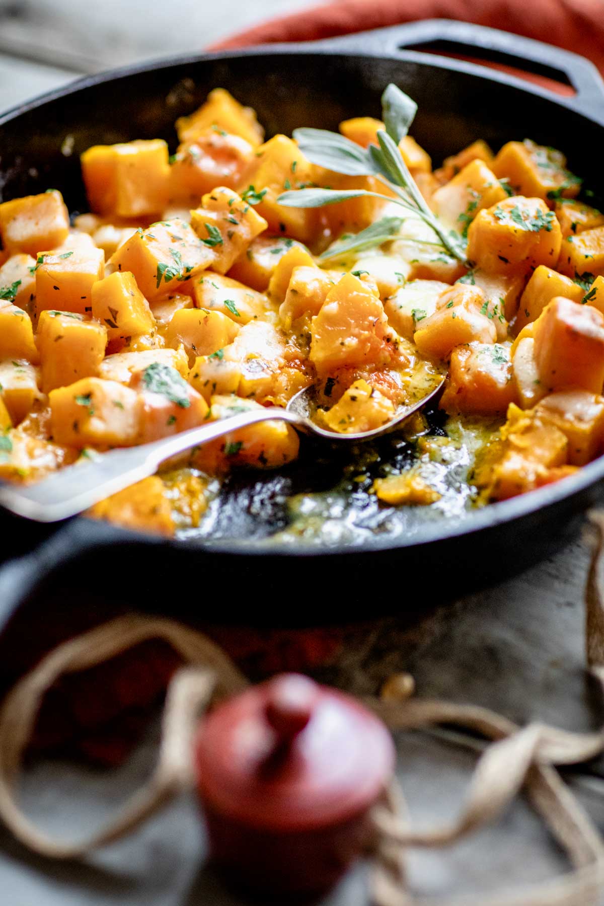 Easy cheesy butternut squash in a cast iron pan with a spoon