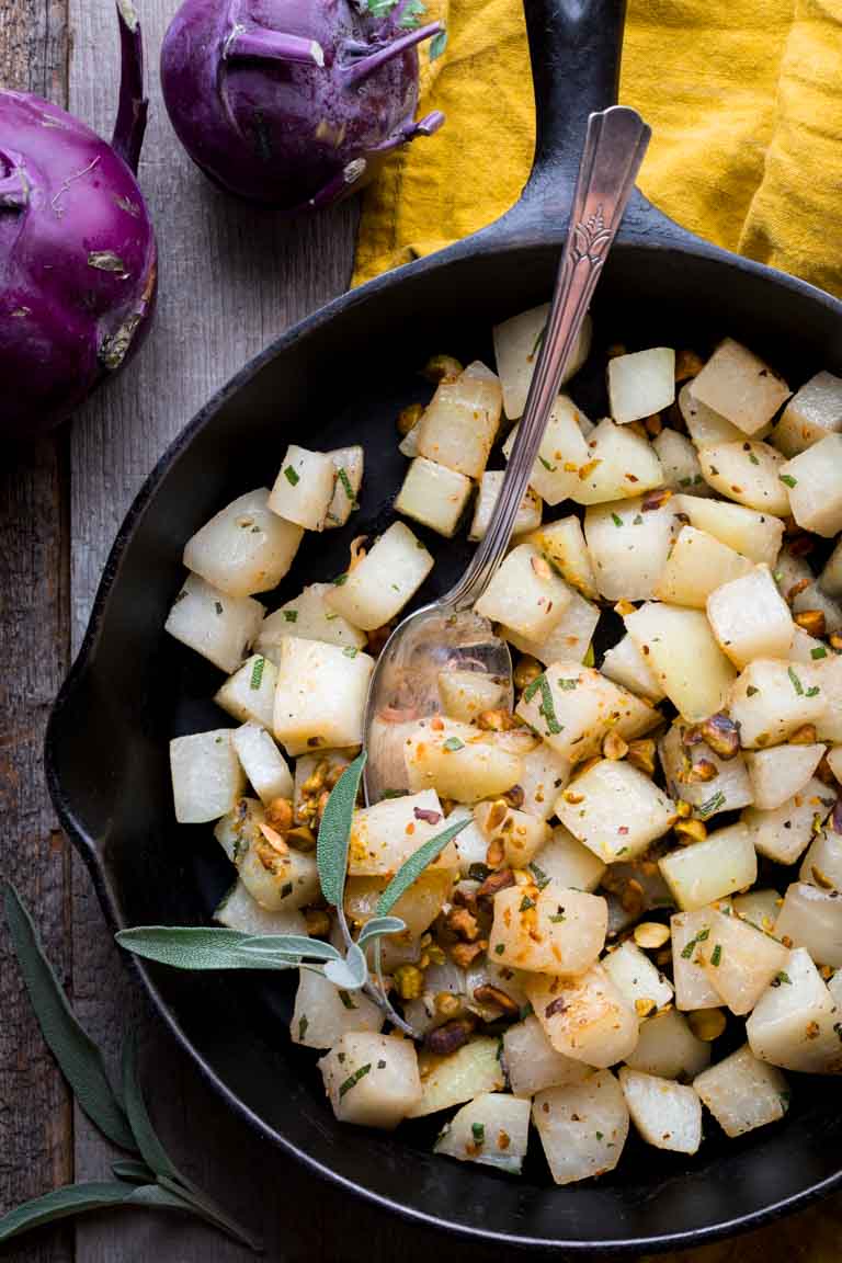 Simple Kohlrabi with Pistachios and Sage in a skillet with a serving spoon