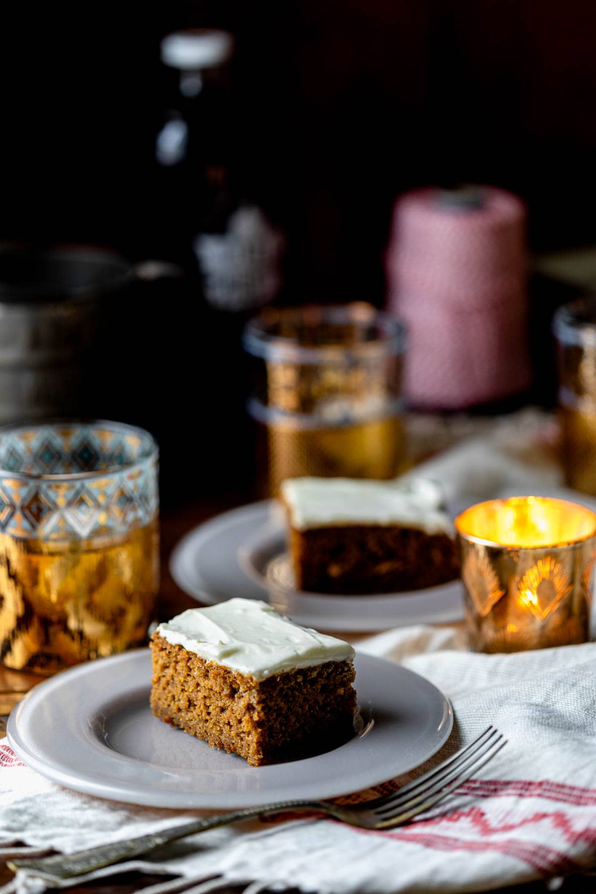 cake slices on plates on a table with votive candles and gold glasses