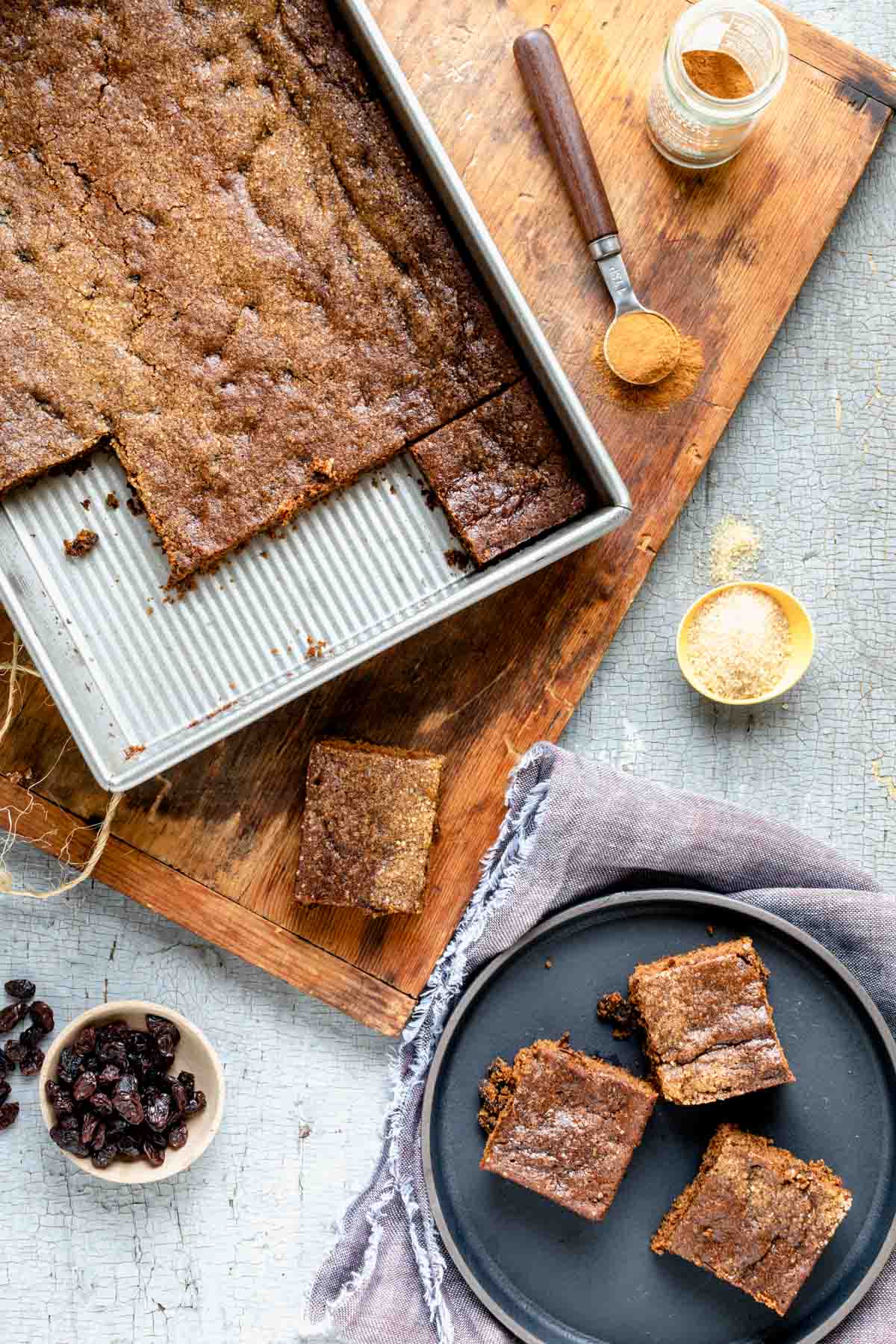 the pan of hermits with a black plate with three hermit bar cookies on it