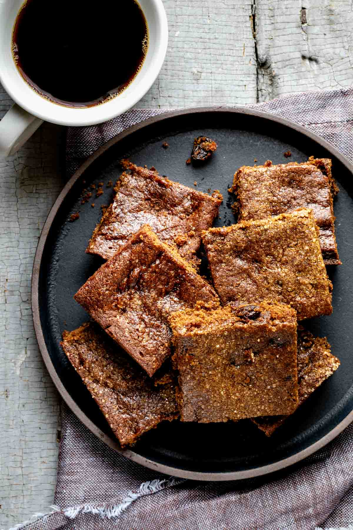 a plate full of hermit bars with a cup of black coffee
