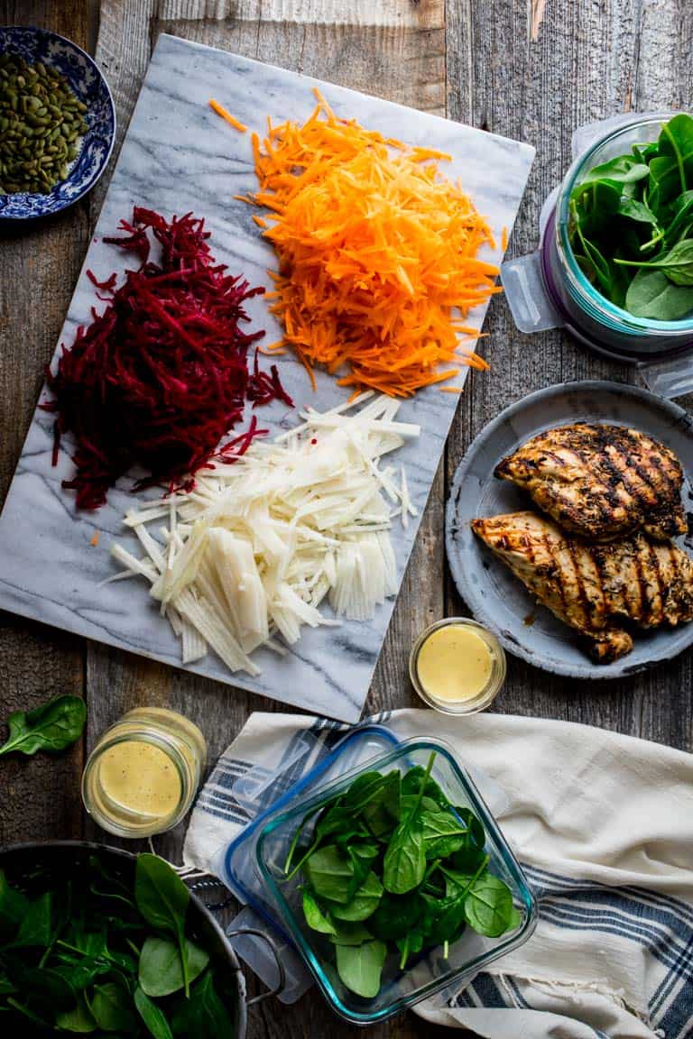Chicken, spinach, beets and carrots laid out on a table