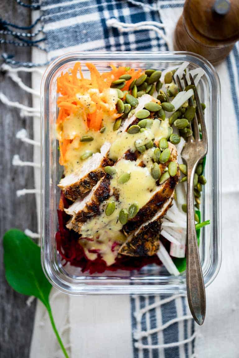 meal prep lunch salad with chicken, seeds and dressing in a to-go container