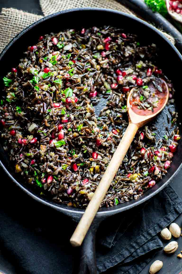 A skillet with wild rice, pomegranate seeds, and pistachios.